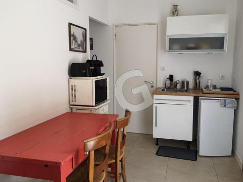 une cuisine avec une table rouge et une petite cuisine avec une table et des chaises dans l'établissement Maison de vacances proche plage et centre, La Tranche sur Mer - FR-1-357-335, à La Tranche-sur-Mer