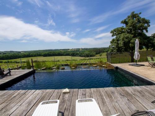 - une piscine avec une terrasse en bois et des chaises dans l'établissement Grande maison avec piscine naturelle et jardin en Dordogne - FR-1-616-463, à Pomport