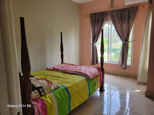 a bedroom with a bed with a colorfulspread and a window at Casa Del Mar Apartments in Brufut