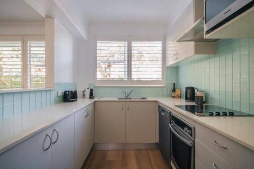 a kitchen with white cabinets and a sink at Quiet Little Manly 1 bed - 3min walk Harbour & Beaches w Level Access in Sydney