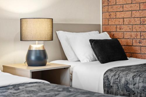 a bedroom with two beds and a lamp on a night stand at Bomaderry Motor Inn in Nowra