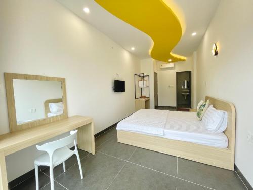 a bedroom with a bed and a mirror and a chair at Baly Hotel Bà Rịa City in Ba Ria