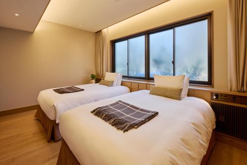 two beds in a room with a large window at Glamdy style hotel suite 川ノ音 in Kyū-karuisawa
