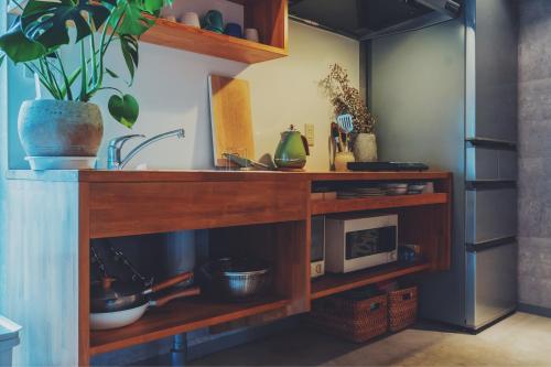 a kitchen shelf with a microwave and a plant at women only nini hostel 伏見稲荷 in Kyoto