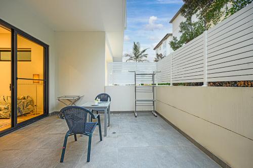 a patio with two chairs and a table and a building at Premium location one bedroom APT with secure car parking - 5 mins Train, Shops in Eastwood