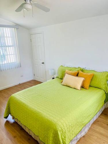 a green bed in a white room with a ceiling at Yellow Beachfront Dream Home in Rosarito Beach