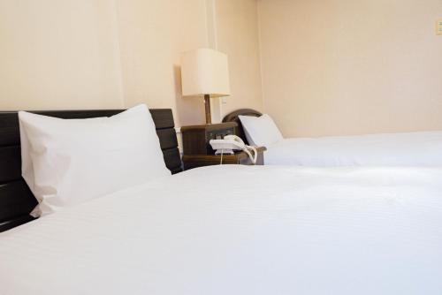 ein Schlafzimmer mit einem großen weißen Bett und einem Telefon in der Unterkunft Hotel Alpha Inn Akita - Vacation STAY 67285v in Akita