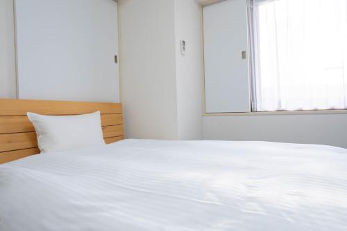 a white bed in a room with a window at Hotel Alpha Inn Akita - Vacation STAY 67280v in Akita
