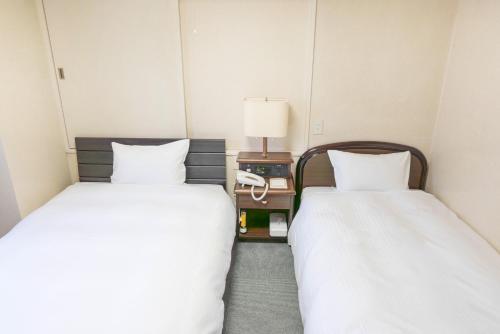 ein Hotelzimmer mit zwei Betten und einer Lampe in der Unterkunft Hotel Alpha Inn Akita - Vacation STAY 67286v in Akita