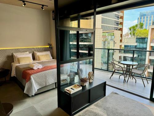 a bedroom with a bed and a balcony with a table at VN Millennium Faria Lima in São Paulo