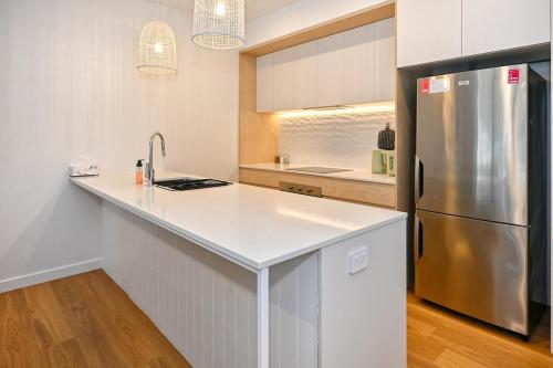 a kitchen with a stainless steel refrigerator and white cabinets at Bokarina Beachside Escape - 6 Guests in Bokarina