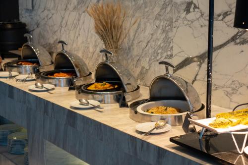 a buffet line with several pans of food at Mövenpick Hotel Sukhumvit 15 Bangkok in Bangkok