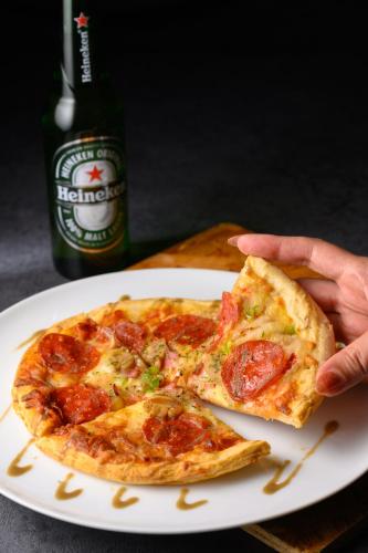 a person holding a slice of pizza on a plate at The Royal Park Canvas - Osaka Kitahama in Osaka