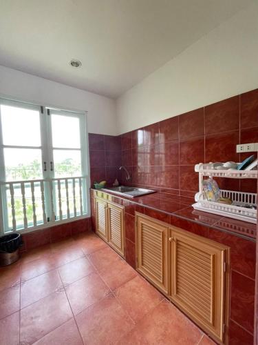 a kitchen with wooden cabinets and a tile floor at Goldengold (Khaoyai) Resort & Spa in Mu Si
