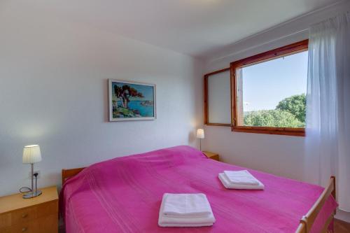 a bedroom with a pink bed and a window at Vila Mirta in Nerezine