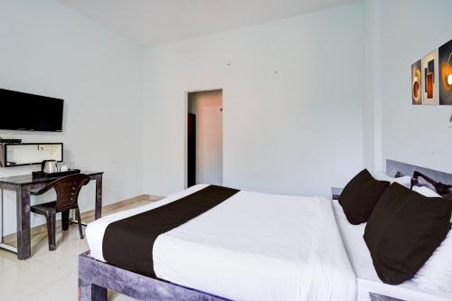 a bedroom with a bed and a desk and a television at Super Collection O Uttarahalli in Bengaluru