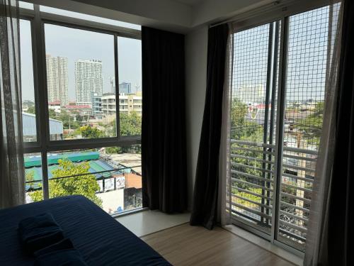 a bedroom with a bed and large windows with a view at GP House Express Sukhumvit 81 in Bangkok