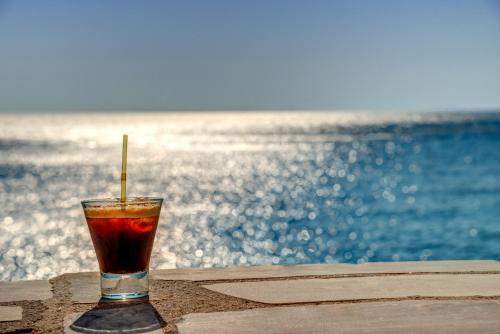 a drink sitting on a table next to the ocean at Apollonion Palace in Ermoupoli