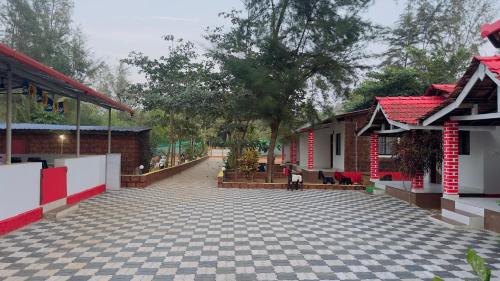 an empty courtyard with two buildings and trees at White Sand beach Stay Resort in Kumta