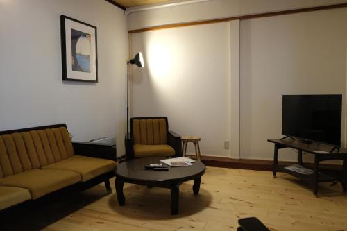 a living room with a couch and a table and a tv at Shinden 5 Bedroom Nozawa Townhouse in Nozawa Onsen
