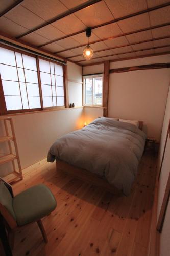 a bedroom with a bed and a chair in it at Shinden 5 Bedroom Nozawa Townhouse in Nozawa Onsen
