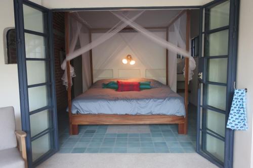 a small bed in a room with glass doors at Casa Clara 2 bedrooms and 2 kitchens with a Large Garden and a Record Player! in Lo de Marcos