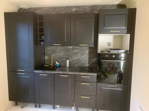 - une cuisine avec des armoires noires et une cuisinière dans l'établissement Beautiful studio with AC close to the sea!, à Cannes