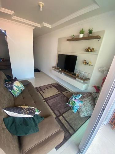 a living room with a couch and a flat screen tv at Apto aconchegante nos Bancários 65m in João Pessoa