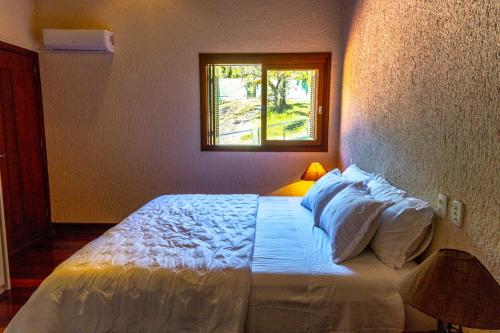 a bedroom with a white bed with a window at Mansão VOAR in Florianópolis