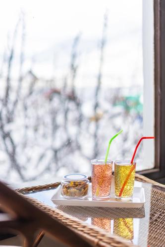 a tray with three drinks on a table with a window at Hotel Sparrow in Pahalgām