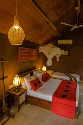 a bedroom with a bed with pillows and a lamp at Gaga Bees Yala in Tissamaharama