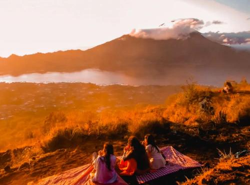 a group of girls sitting on a blanket looking at a mountain at Ayra Batur Sunrise Jeep in Kubupenlokan