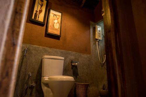 a bathroom with a toilet and a phone on the wall at Gaga Bees Yala in Tissamaharama