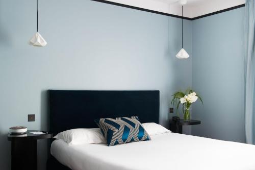 a bedroom with two beds and two pendant lights at L'Hôtel in Nantes