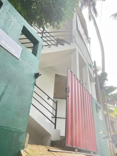 a white building with a red door and stairs at The Villa Sea Breeze in Talpe