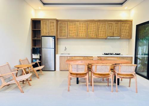 Una cocina con mesa y sillas y un refrigerador. en Ergio House, en Tumbak Bayuh