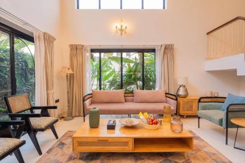 a living room with a couch and a table at ELIVAAS Bogenvilla Luxe 3 BHK Villa Near Ozran Beach in Assagao