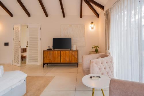 a living room with a couch and a tv at ELIVAAS Bogenvilla Luxe 3 BHK Villa Near Ozran Beach in Assagao