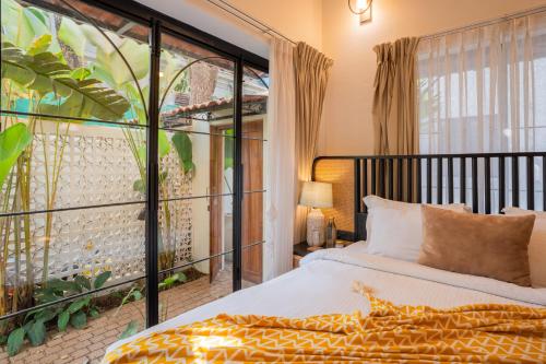 a bedroom with a bed and a large window at ELIVAAS Bogenvilla Luxe 3 BHK Villa Near Ozran Beach in Assagao