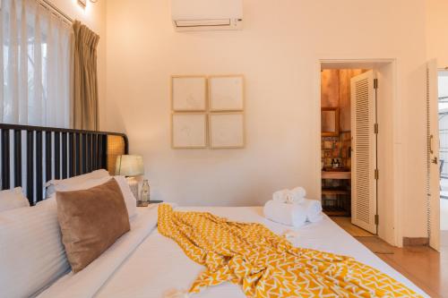 a bedroom with a bed with a yellow blanket on it at ELIVAAS Bogenvilla Luxe 3 BHK Villa Near Ozran Beach in Assagao