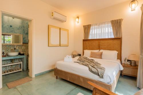 a bedroom with a large bed with a wooden headboard at ELIVAAS Bogenvilla Luxe 3 BHK Villa Near Ozran Beach in Assagao