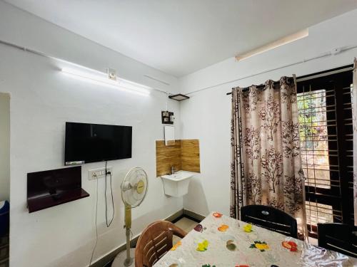 a room with a dining table and a tv on the wall at Alappattu meadows in Kottayam