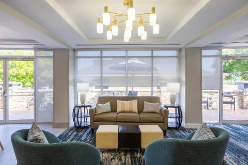 a living room with a couch and chairs and windows at Holiday Inn Anderson by IHG in Anderson