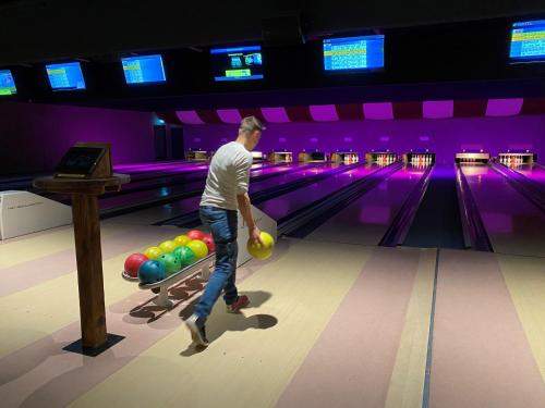 a man is playing bowling in a bowling alley at Ferienhauspark Asgard in Damp in Damp