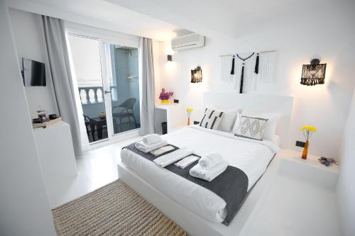 a white bedroom with a large white bed and a window at Çamlık 87 Hotel Ayvalık in Ayvalık