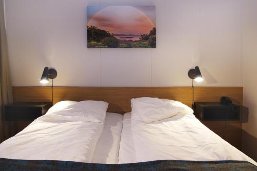 1 cama con 2 almohadas blancas y una foto en la pared en Hamarøy Hotel, en Innhavet