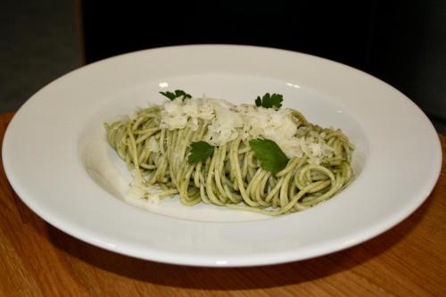 a white plate of pasta on a wooden table at STEELHOUSE Hotel in Třinec