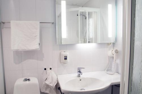 a white bathroom with a sink and a toilet at Hamarøy Hotel in Innhavet