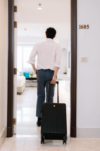 a man is walking into a room with a suitcase at Centre Point Plus Hotel Silom - Newly Renovated in Bangkok