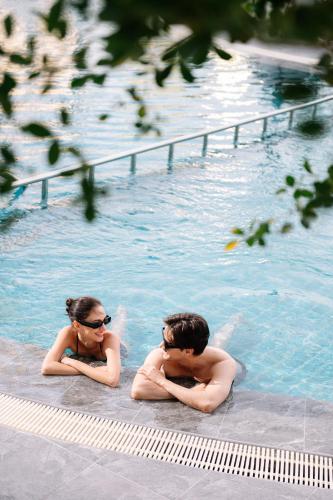 a man and a woman in a swimming pool at Centre Point Plus Hotel Silom - Newly Renovated in Bangkok